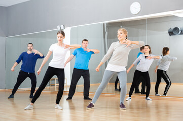 Smiling females and males doing Zumba dance workout during group classes in fitness center