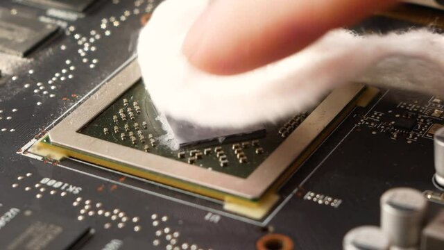 Close-up preparation for installing a heatsink on a personal computer processor, removing old thermal paste from the processor with a cotton swab. Computer upgrade