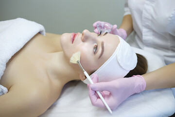 Naklejka premium Cosmetologist does face peeling of a beautiful woman. Women's cosmetology in the beauty salon