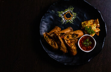 Top view of Cheese & Bell Pepper Roll with sweet suace and beautiful garnishing kept on wooden surface.