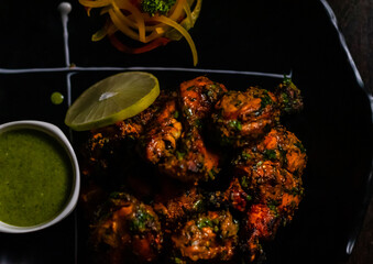 Top view of Roasted Chicken with green spicy sauce on garnished plate.