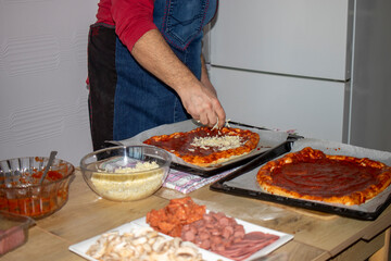  A man is prepearing Homemade pizza. it is in preparation to be cooked.