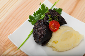 Traditional Spanish blood sausage with rice served with mashed potato, cherry tomato and greens