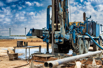Work of a drilling rig at a construction site against a background of blue sky. Exploration of...
