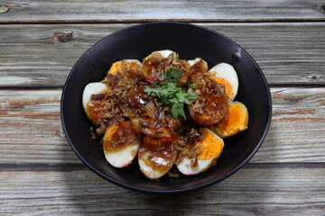 Pile of cutting boiled egg seasoning with sweet tamarind sauce serving on the plate. Famous traditional ancient menu in Asia restaurant. 