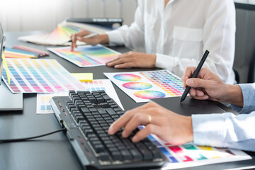 graphic designer team working on web design using color swatches editing artwork using tablet and a...