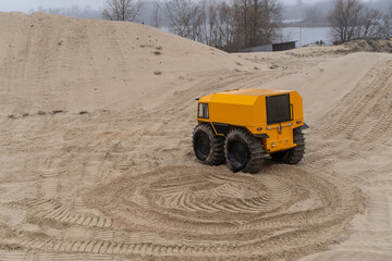 Obraz premium Yellow all-terrain vehicle driving and leaving twisted marks in the sand