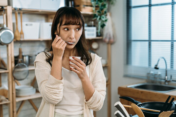 A pretty Asian girl show us that she ate the tasty new fruit yogurt in the kitchen. healthy...
