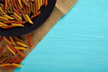 Raw pasta on a black plate, top view, copy space