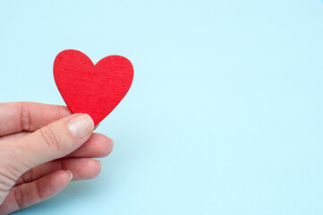 Red heart in hand on blue background