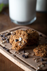 Oatmeal chocolate chip cookie with glass of milk. Healthy cookies on natural wooden background.