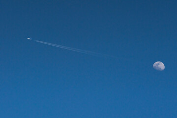 Returning from the Moon. Abstract background of clear blue sky, Moon, and airplane