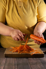 The cook peels a carrot with a red peeler from the peel