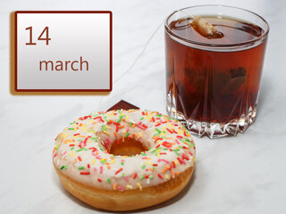 March 14 ,14th day of the month. Calendar with date and a cupcake with glass of tea on table at home.. Spring month. Day of the year concept.