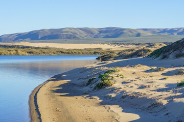 Sand dunes, blue river, green hills and mountains on background. Guadalupe-Nipomo Dunes, CA