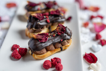 creamy chocolate eclair with edible flowers, rose petals and freeze dried raspberries 