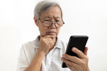 Confused asian senior woman with puzzled looks holding smartphone,confusing by information while using mobile phone or unable to understand,complex technology problems difficult to use for the elderly