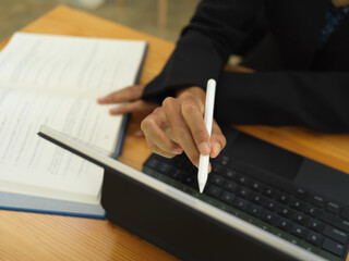 Businesswoman hand with stylus pen working with digital tablet and textbook