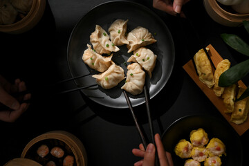 Female hand with chopstick picking Dimsum dumplings on the table in Chinese restaurant