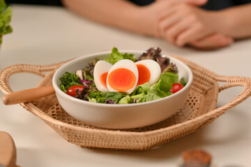 A plate of of salad with boiled eggs, lettuce and tomato on wicker tray in restaurant