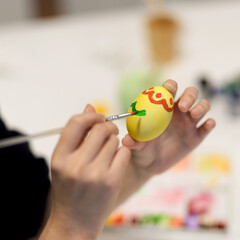 Female hand painting Easter egg with paintbrush to prepare for easter festival
