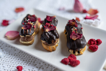 creamy chocolate eclair with edible flowers, rose petals and freeze dried raspberries  - 415994764