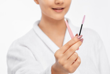 Young attractive woman in a white coat plucking eyebrows. Professional make-up and cosmetic skin care.