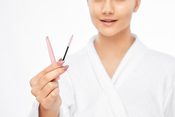 Young attractive woman in a white coat plucking eyebrows. Professional make-up and cosmetic skin care.