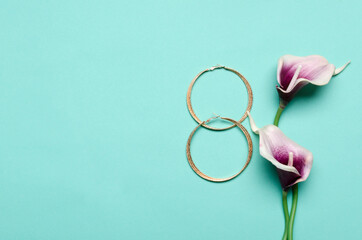 Top view of female earrings and flowers on the blue background.Concept of woman day