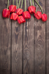 Fototapeta na wymiar red tulips on dark wooden background