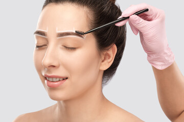 Make-up artist makes markings with white pencil for eyebrow and paints eyebrows. Professional...