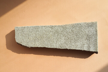 concrete chip on a beige paper background in harsh light with shadows. flat layout, top view.