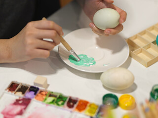 Hands painting egg with poster colour preparing for Easter festival
