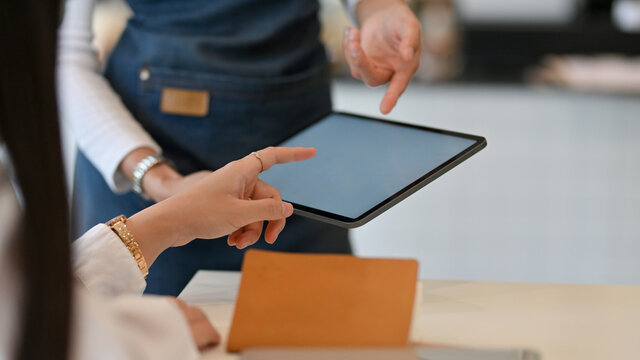 Female customer ordering menu on digital tablet in waitress hands