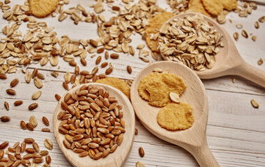 wheat and cereal scattered on the table wooden spoons kitchen board