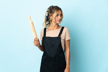 Young blonde Uruguayan cooking woman isolated on blue background looking to the side