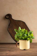 Fresh green mint leaves in a metal cup on a wooden dark background. Mentha piperita plant.