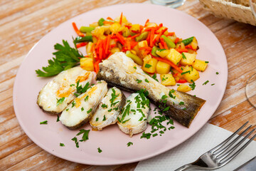 Oven baked hake with vegetable garnish and parsley
