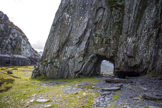 Arch through rocky mountain covered in moss in Dinorwig quarry, Llanberris, North Wales