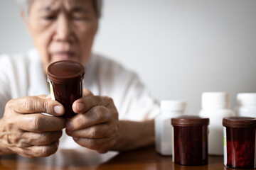 Asian senior grandmother reading medical information before taking of medicine,read the nutrition...