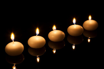 Row of round candles lite in the dark.