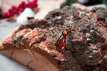 Suspension in the form of a beetle of bronze and amber on a wooden background