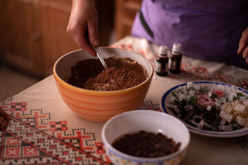 hands of a woman mixing ground walnut with cocoa, raisins and Turkish delicacies in the kitchen....