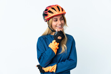 Young blonde Uruguayan cyclist woman isolated on background looking to the side and smiling