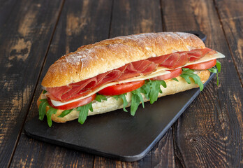 Sandwich with prosciutto, tomatoes, arugula and cheese. Healthy eating. Diet.