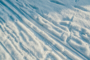 Draufsicht auf Spuren vom Schlitten und Ski im Schnee bei Sonnenschein im Winter