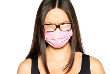 Angry young woman with a face medical mask and foggy glasses