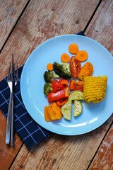 Oven roasted colorful vegetables are waiting for you in the cyan plate, on the wooden background, let's try it! Bon appetit