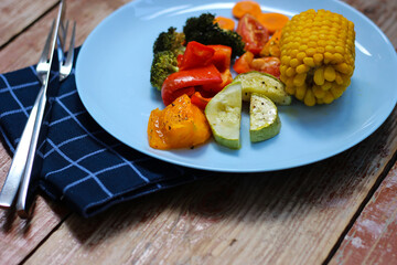 Oven roasted colorful vegetables are waiting for you in the cyan plate, on the wooden background, let's try it! Bon appetit