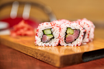 Roll with tuna and cucumber on wooden board. Close-up, selective focus